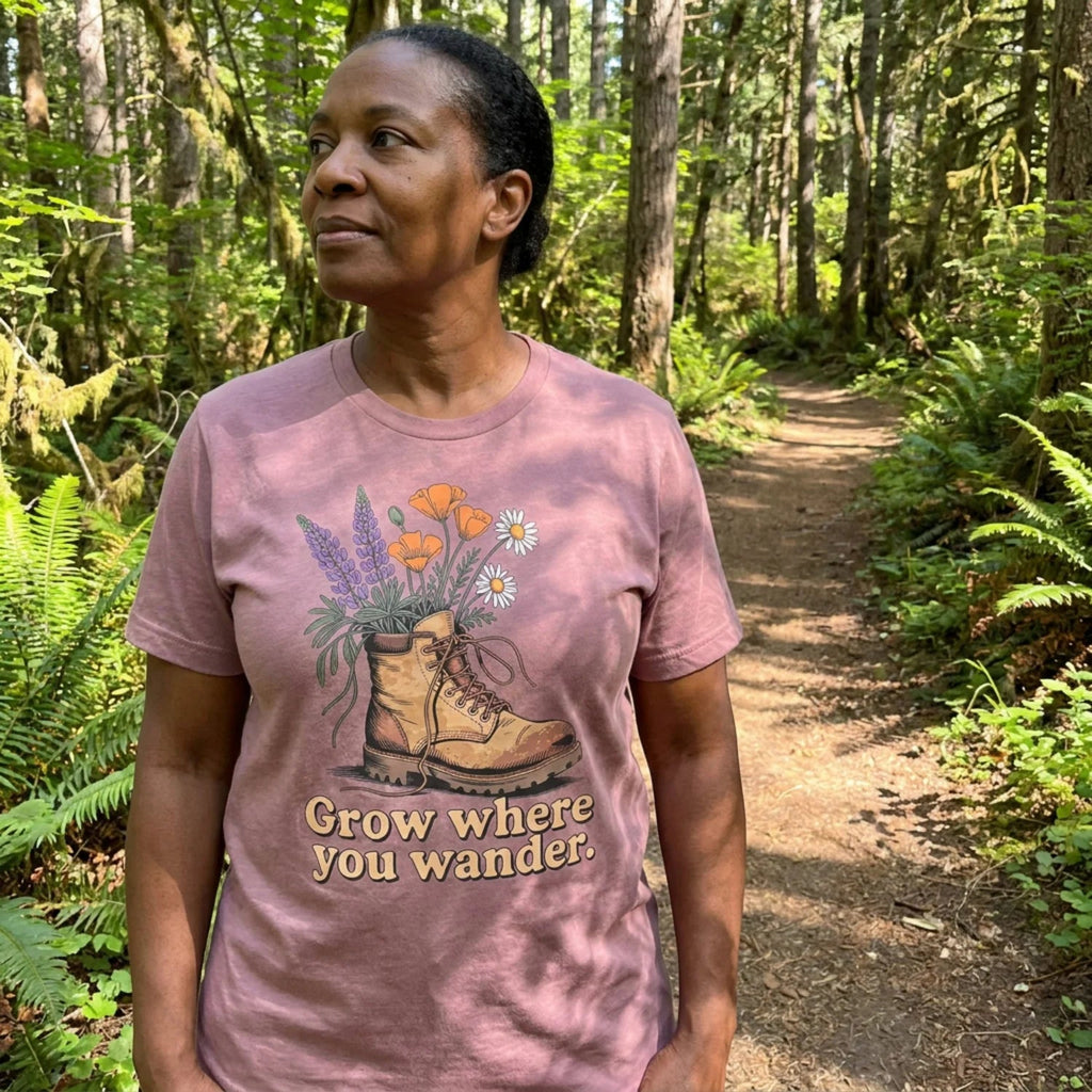 Woman wearing dusty rose hiking tee with boot and flowers in forest