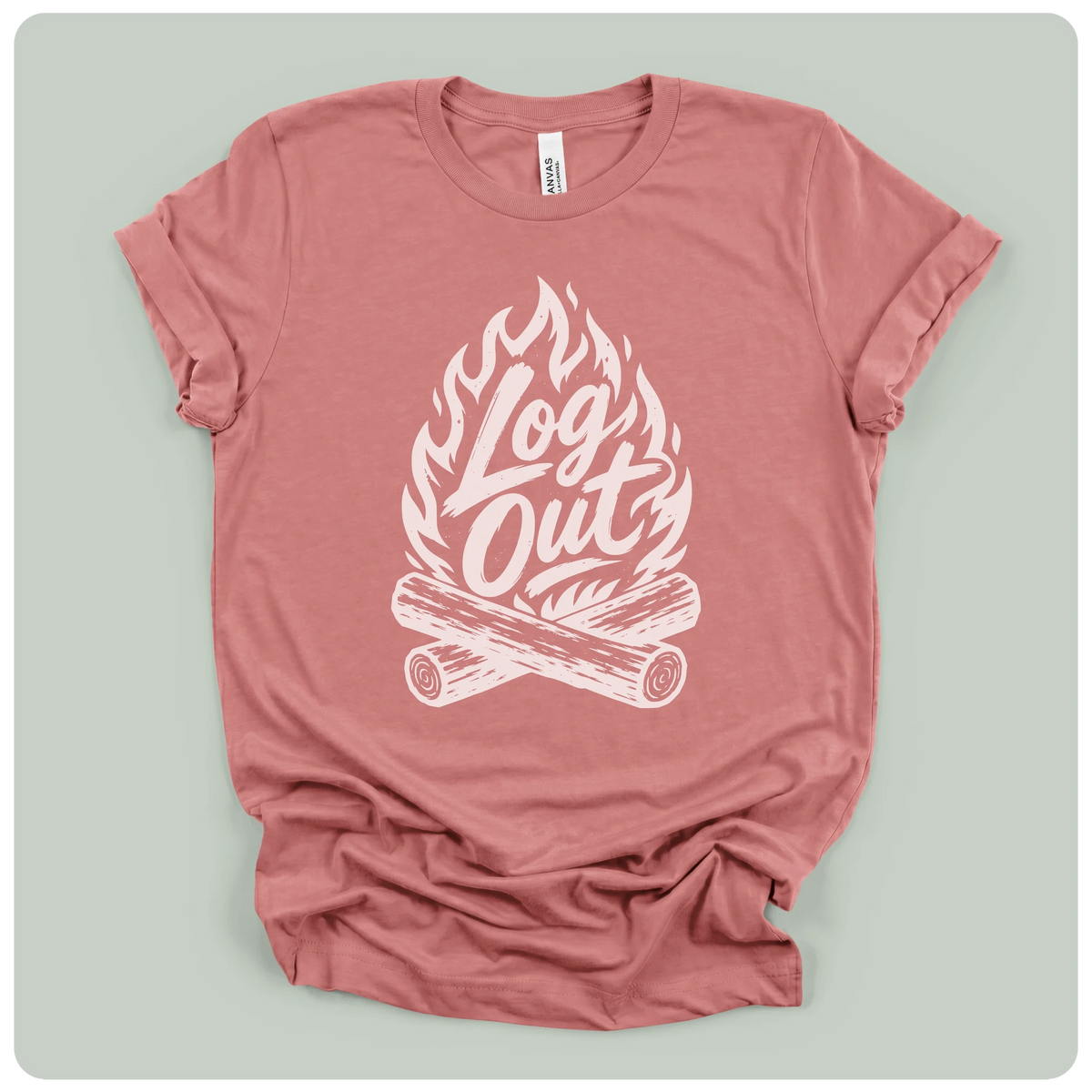 A dusty rose short-sleeve t-shirt with a white graphic print of a campfire and the words 'Log Out' in script, laid flat on a light sage green background.